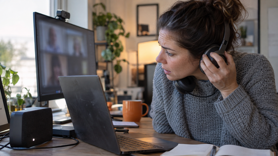 Remote worker on a video call wearing a headset, with a separate speaker on the desk