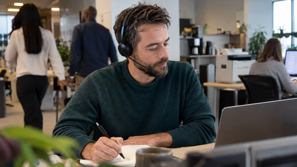 Office worker using a boom microphone headset in a busy workplace