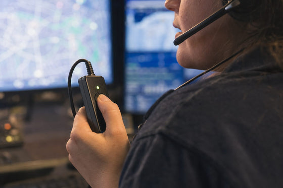 Dispatcher pressing the push-to-talk button on a headset amplifier while speaking into a boom microphone