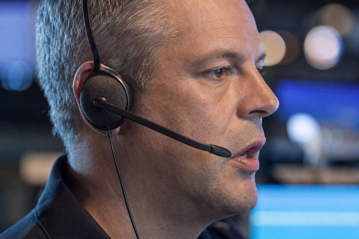 Close-up of a dispatcher speaking into the boom microphone of a single-ear headset